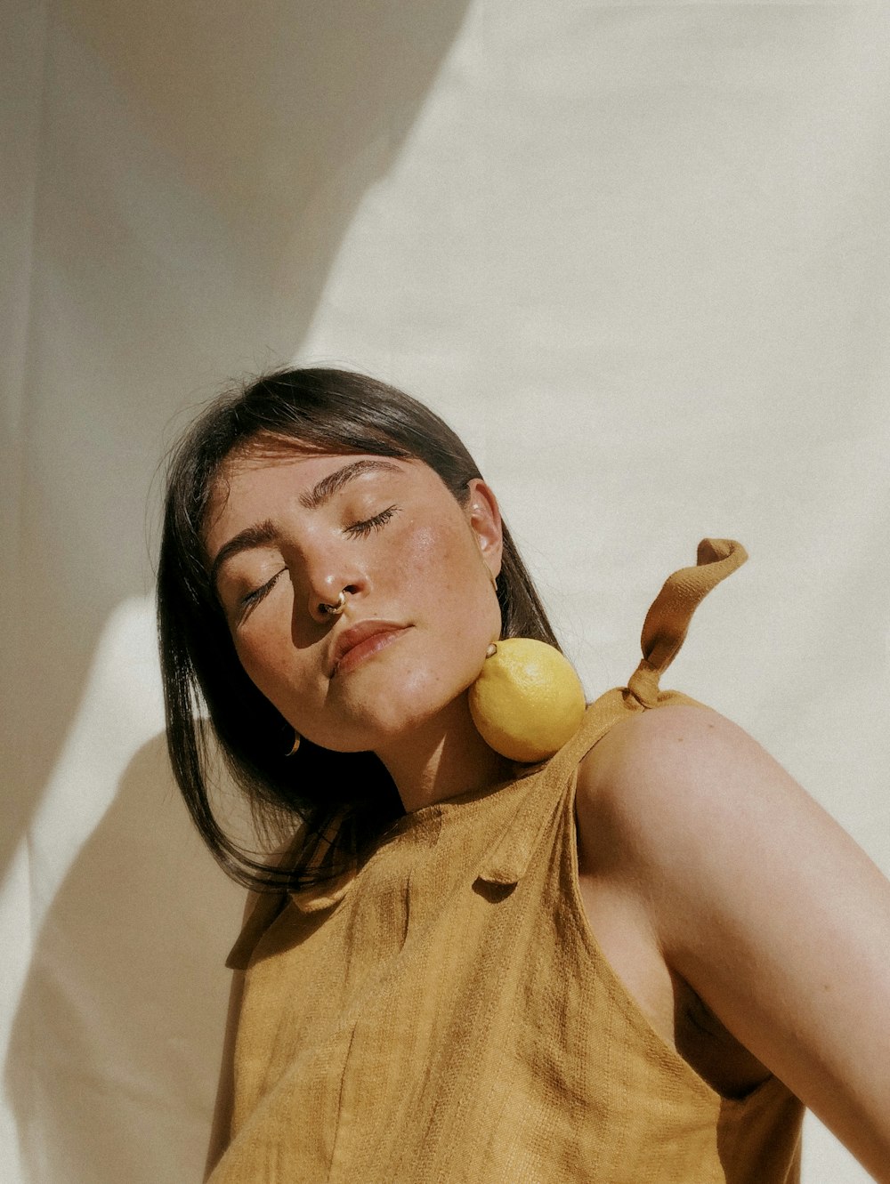 woman in yellow sleeveless dress holding yellow fruit