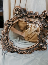 brown wooden framed mirror on white textile