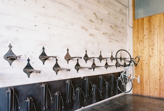 A concrete wall features multiple metal bicycle racks, with one bicycle mounted vertically on the right side. The opposite wall is covered with wooden paneling, adding a rustic touch to the industrial vibe. The floor is made of polished concrete, enhancing the minimalist and functional design.