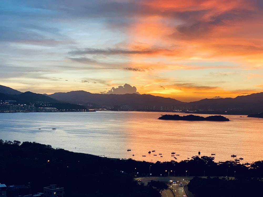 silhouette of mountain near body of water during sunset