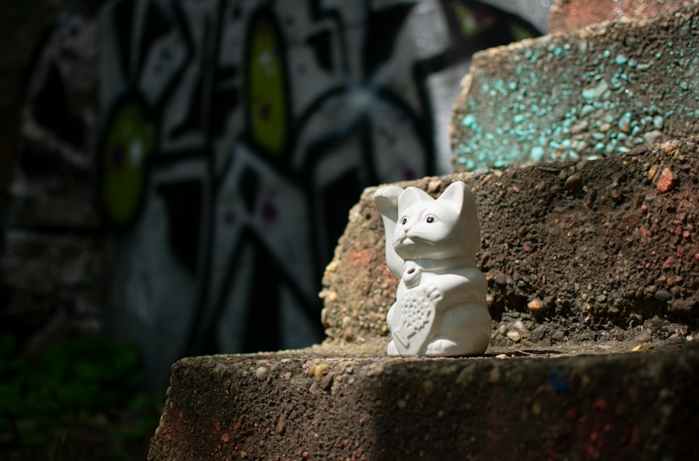 Statuetta di gatto in ceramica bianca su superficie in cemento marrone