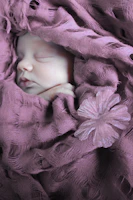 A gentle doula soothing a sleeping newborn wrapped in a soft blanket.