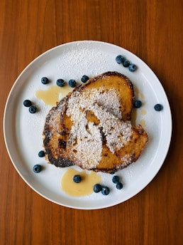 Close-up of golden egg nog French toast dusted with powdered sugar on a rustic plate.