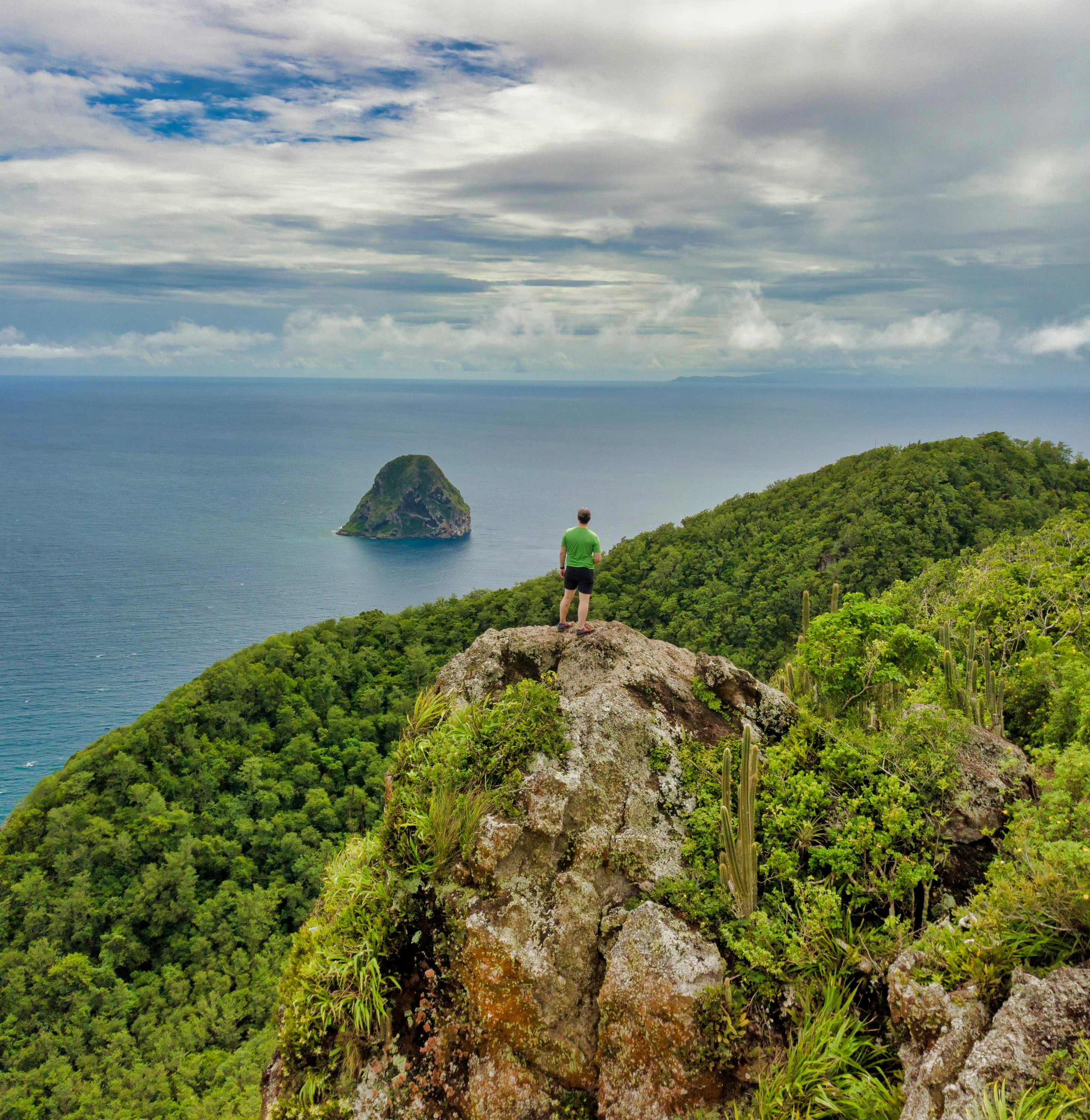 Man standing on rocky cliff looking out at ocean off coast of Martinique
