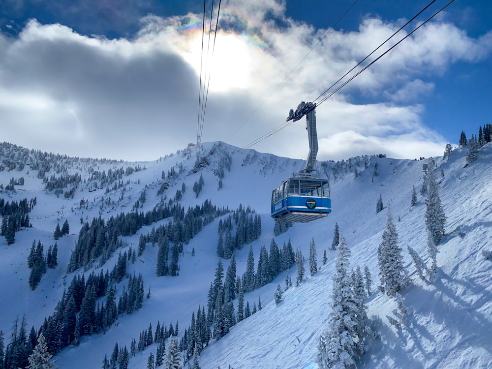 white and blue cable car over snow covered mountain