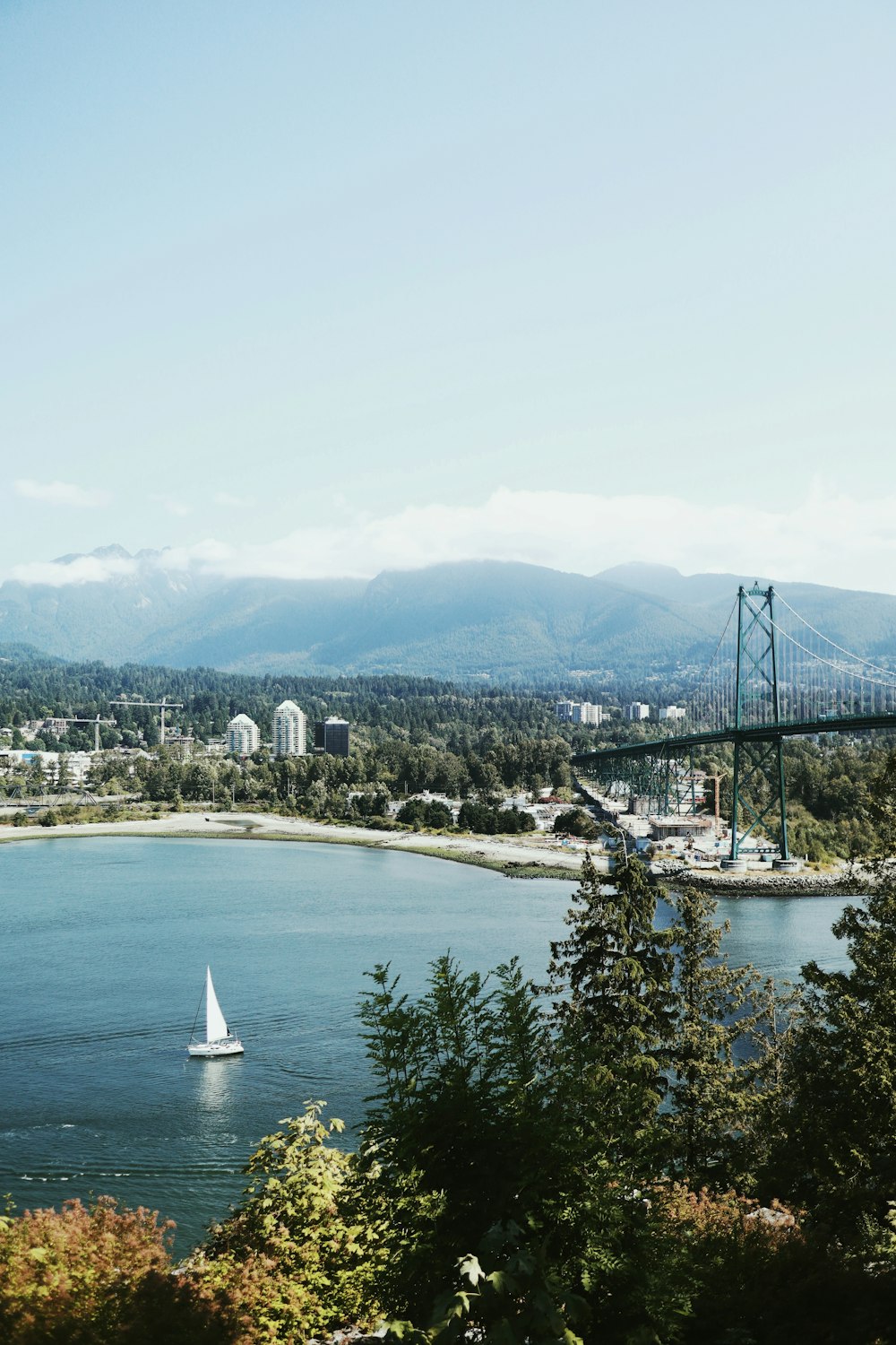 white sailboat on body of water near bridge during daytime