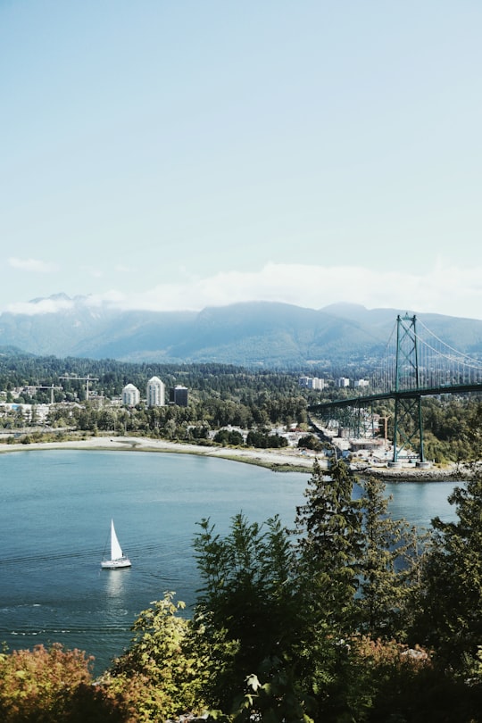 white sailboat on body of water near bridge during daytime in Stanley Park Canada