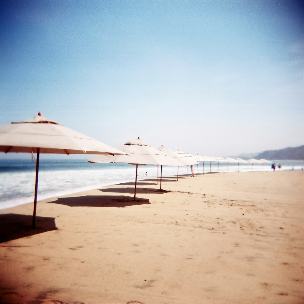 white and brown beach umbrellas on beach during daytime