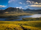green and brown mountains near body of water under blue sky during daytime