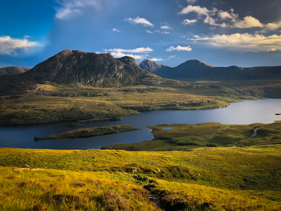 green and brown mountains near body of water under blue sky during daytime