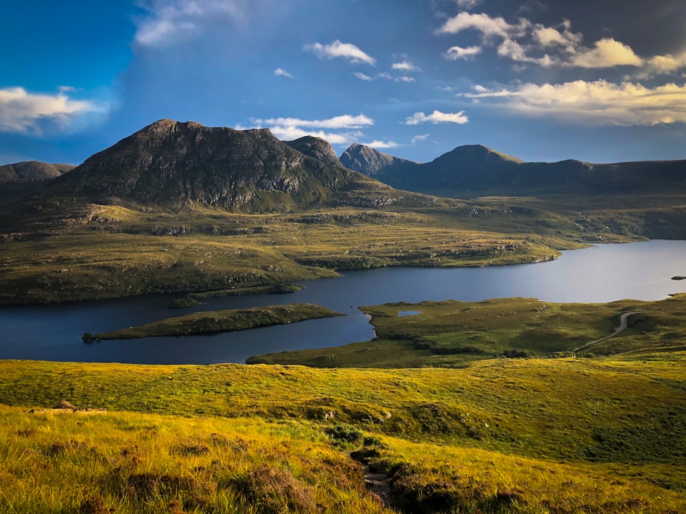 green and brown mountains near body of water under blue sky during daytime