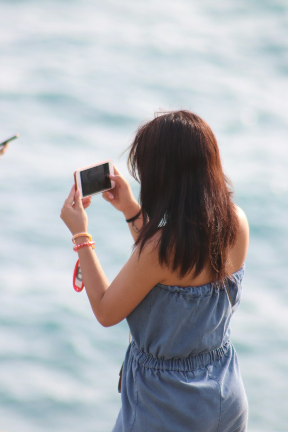 woman in blue denim shorts holding black smartphone