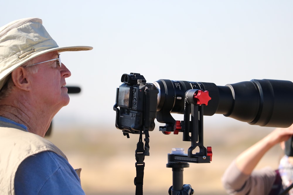 man in blue shirt holding black dslr camera