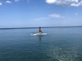 Group of people practicing yoga on paddleboards in calm ocean waters.