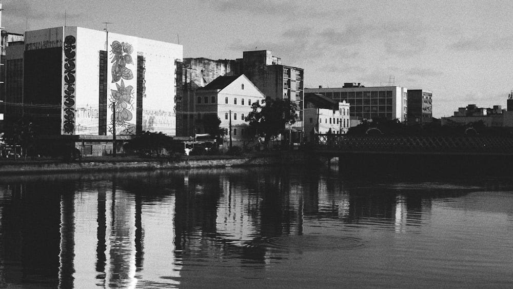 Photo en niveaux de gris de maisons près d’un plan d’eau