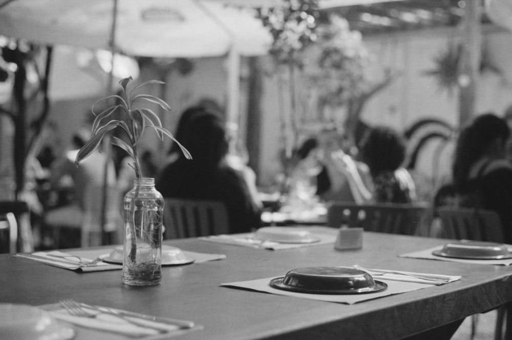 grayscale photo of people sitting by the table