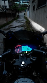 Close-up of a rider’s gloved hand gripping the throttle, with the dashboard lit up in bright orange against the dark background.
