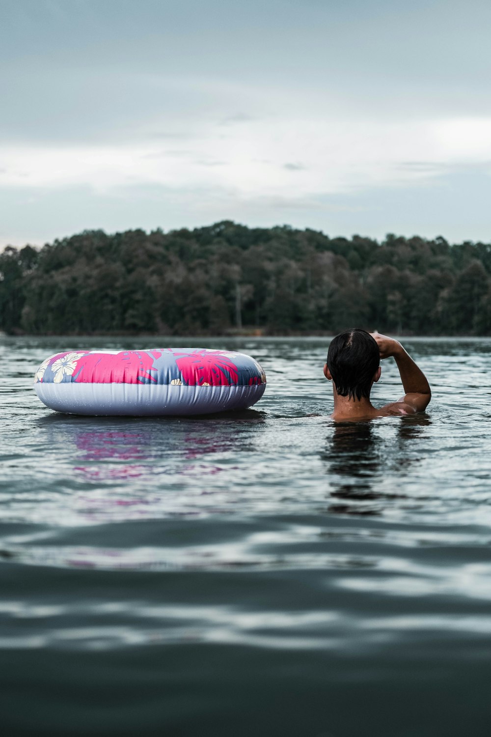 Mujer en anillo inflable rosa y blanco sobre el agua