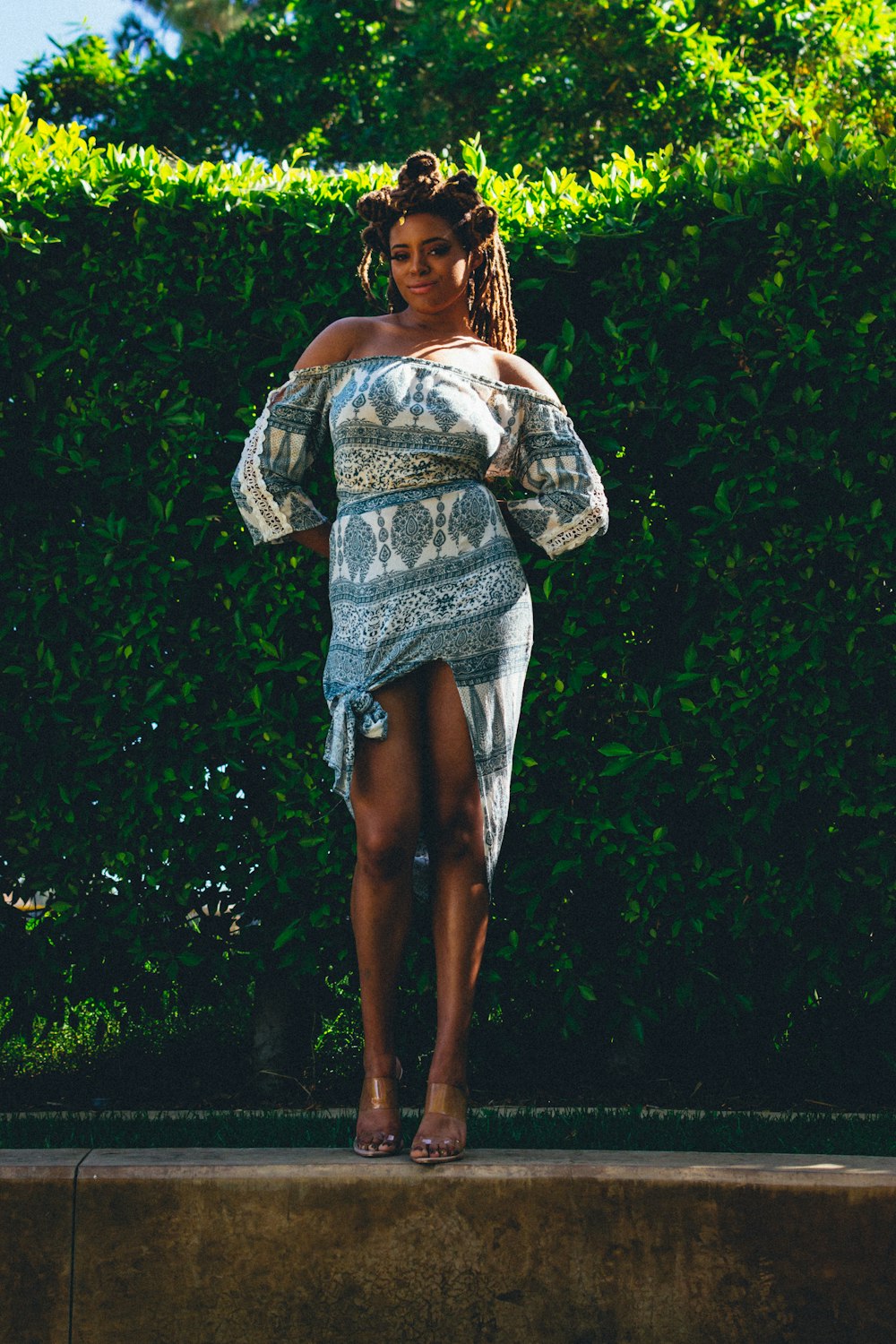 woman in white and black floral dress standing on green grass during daytime