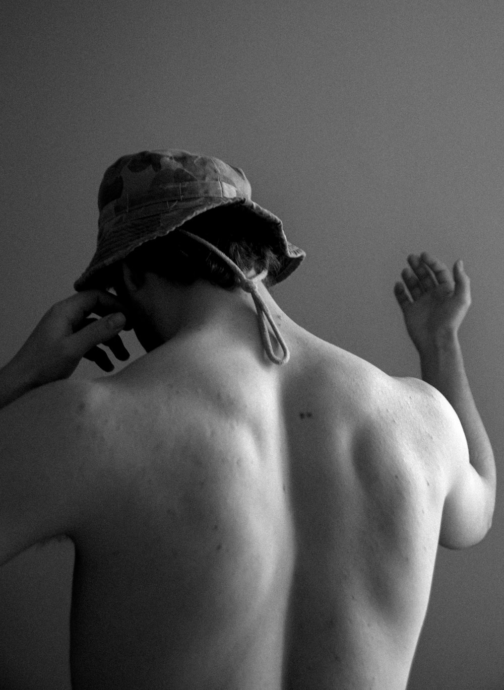 topless man wearing black and white camouflage cap