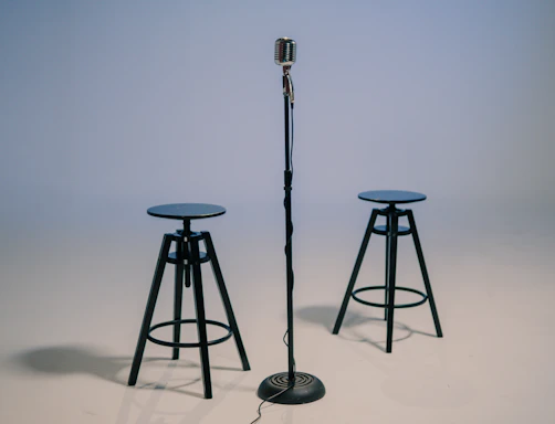 A vintage microphone resting on a wooden table surrounded by old dance photographs and film reels.