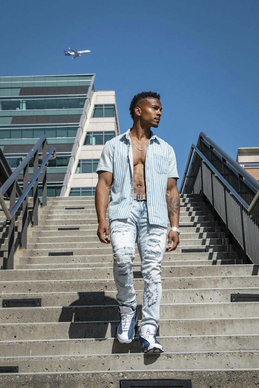 man in white button up shirt and white pants standing on stairs during daytime