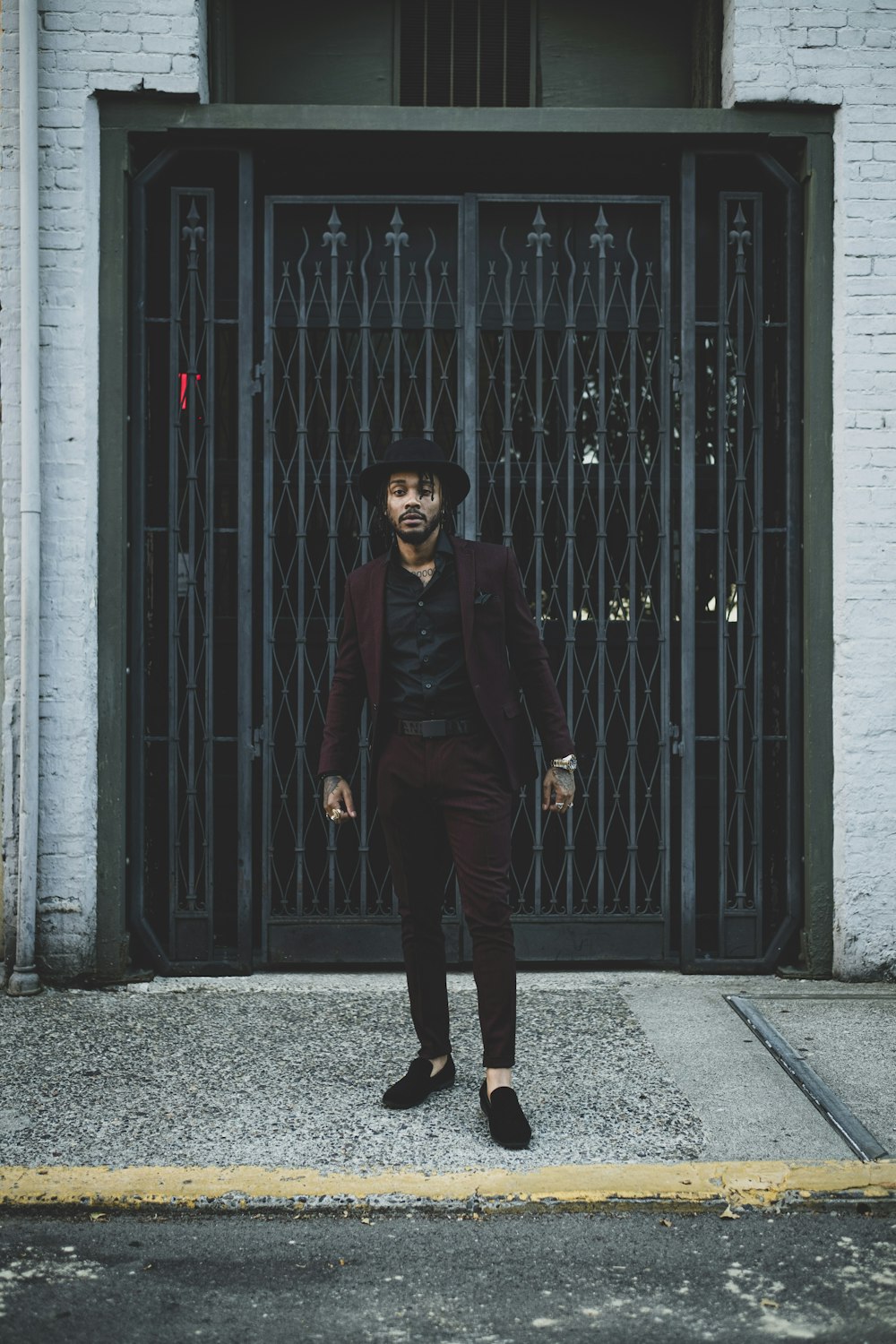 man in black coat standing beside black steel gate during daytime