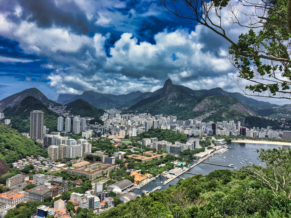 city buildings near mountain under white clouds and blue sky during daytime