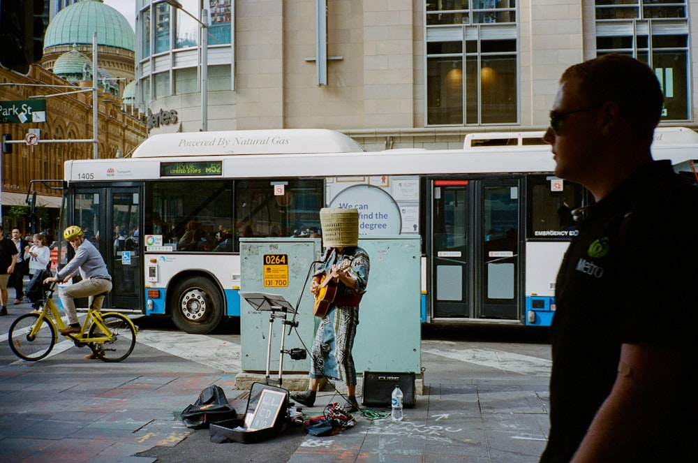 man in black jacket standing near white bus during daytime