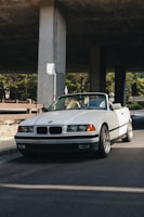 white bmw coupe parked near white concrete building during daytime