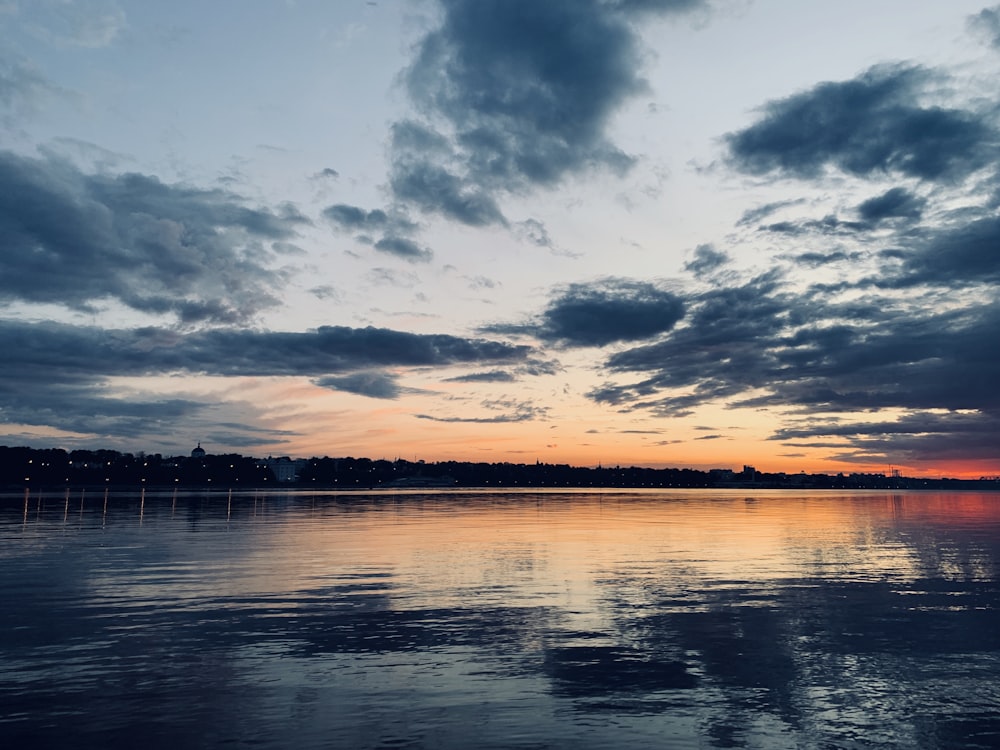 body of water under cloudy sky during sunset