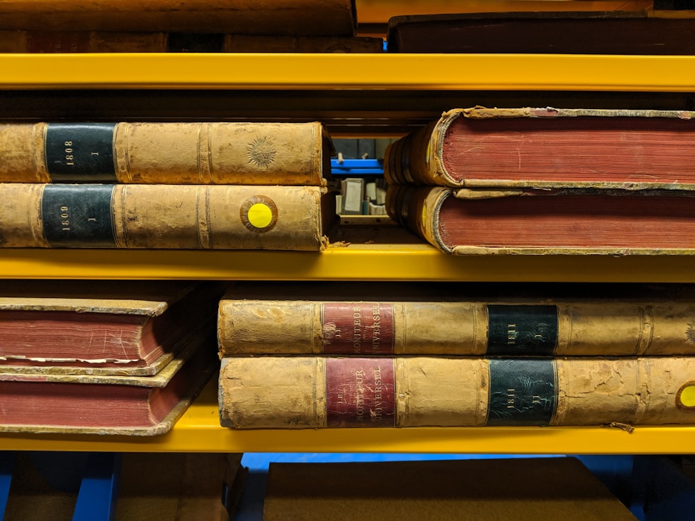 stack of books on yellow wooden shelf