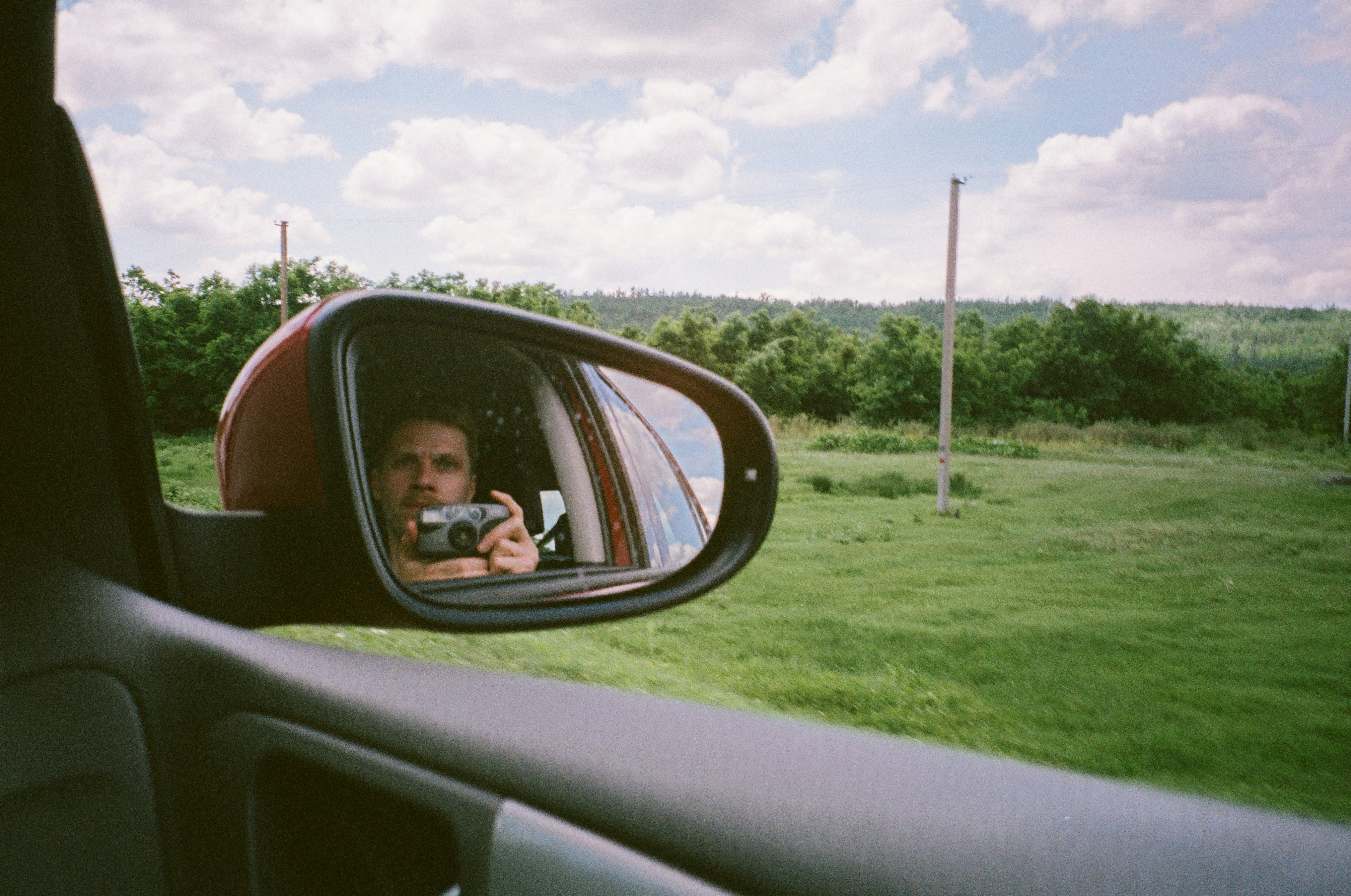 a man taking a picture of himself in the side mirror of a car
