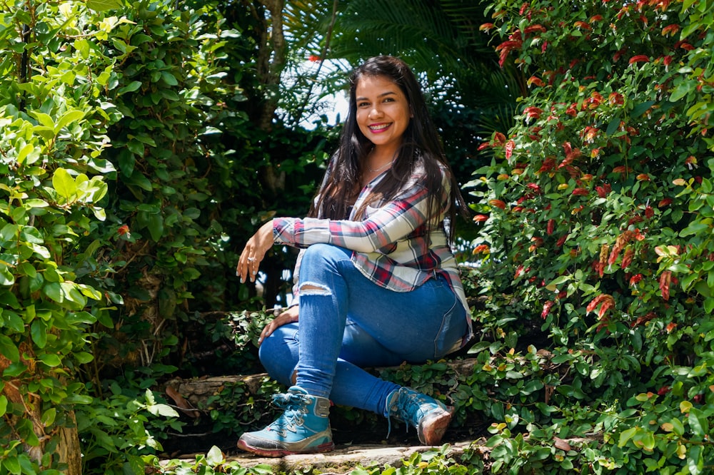 Mujer en jeans de mezclilla azul sentada sobre hojas secas marrones