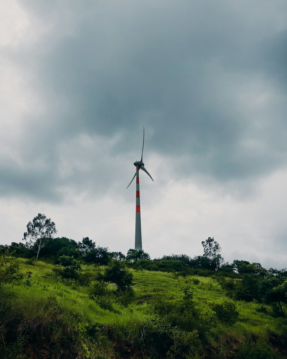 white and red windmill on green grass field under white clouds during daytime