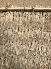 Artisan hands weaving bamboo strips to create traditional bahareque walls.