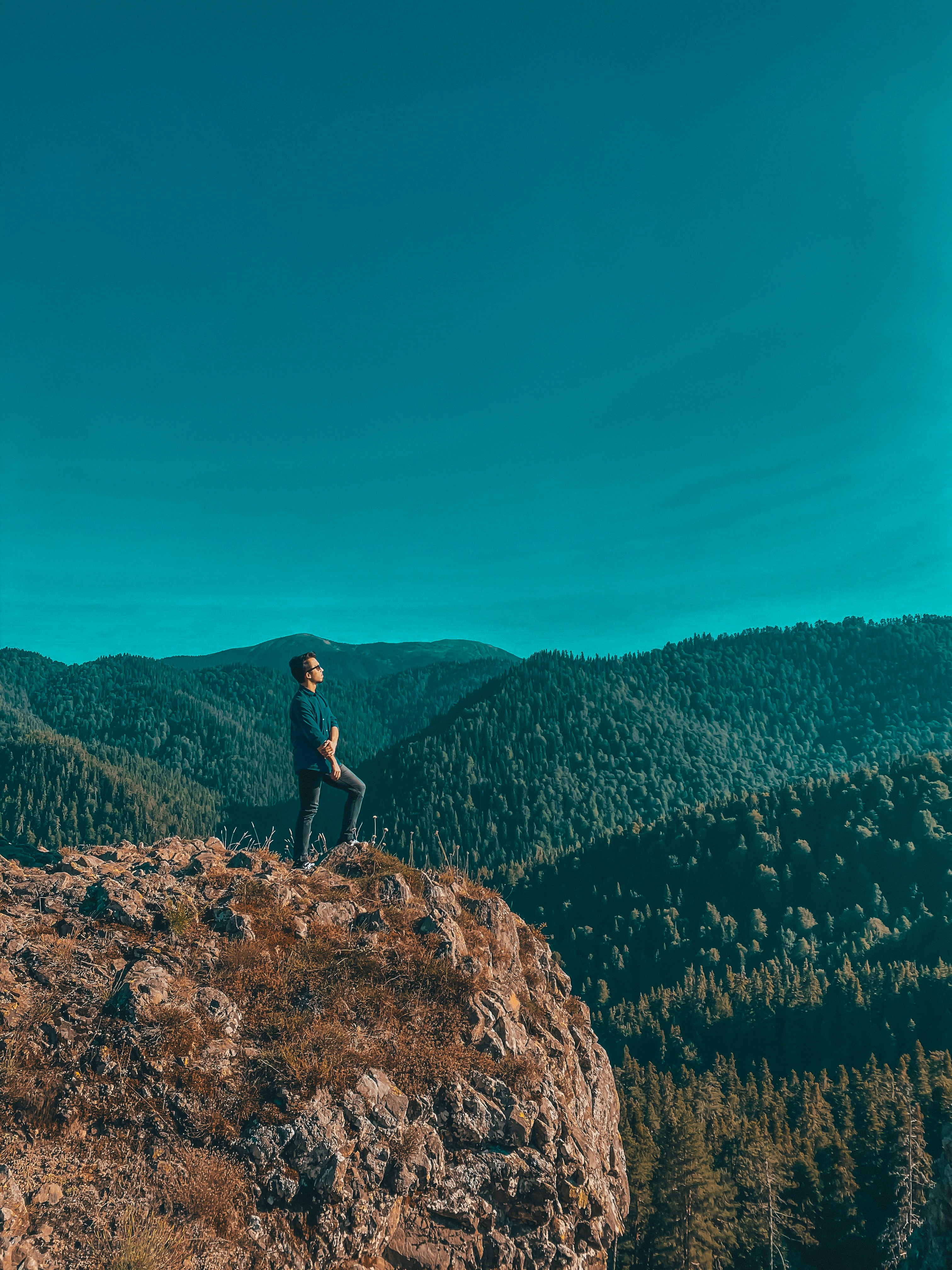 man in black shirt standing on brown rock during daytime