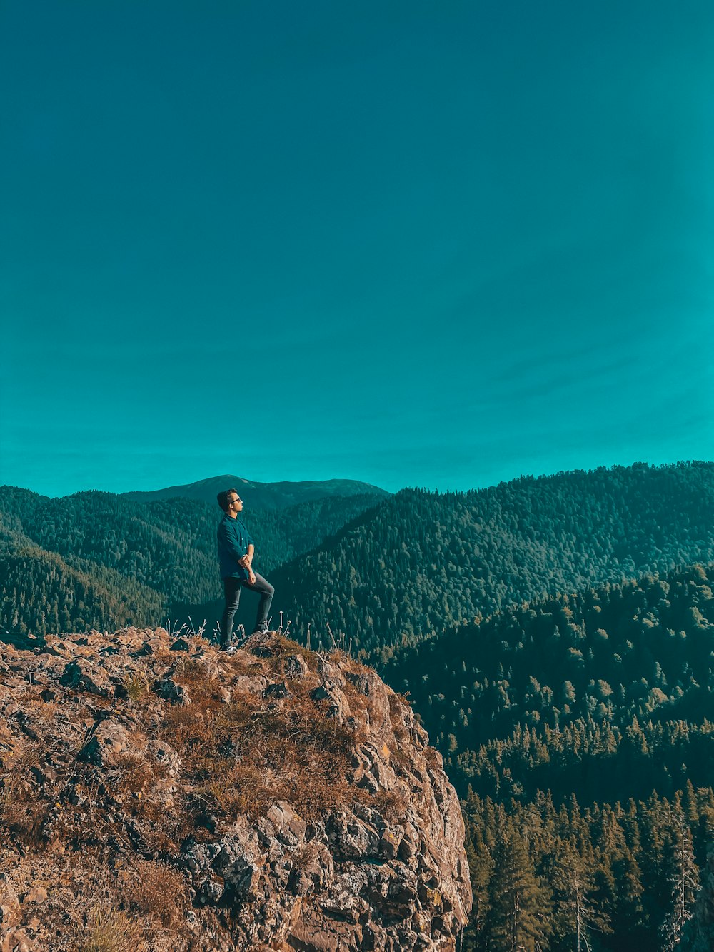 man in black shirt standing on brown rock during daytime