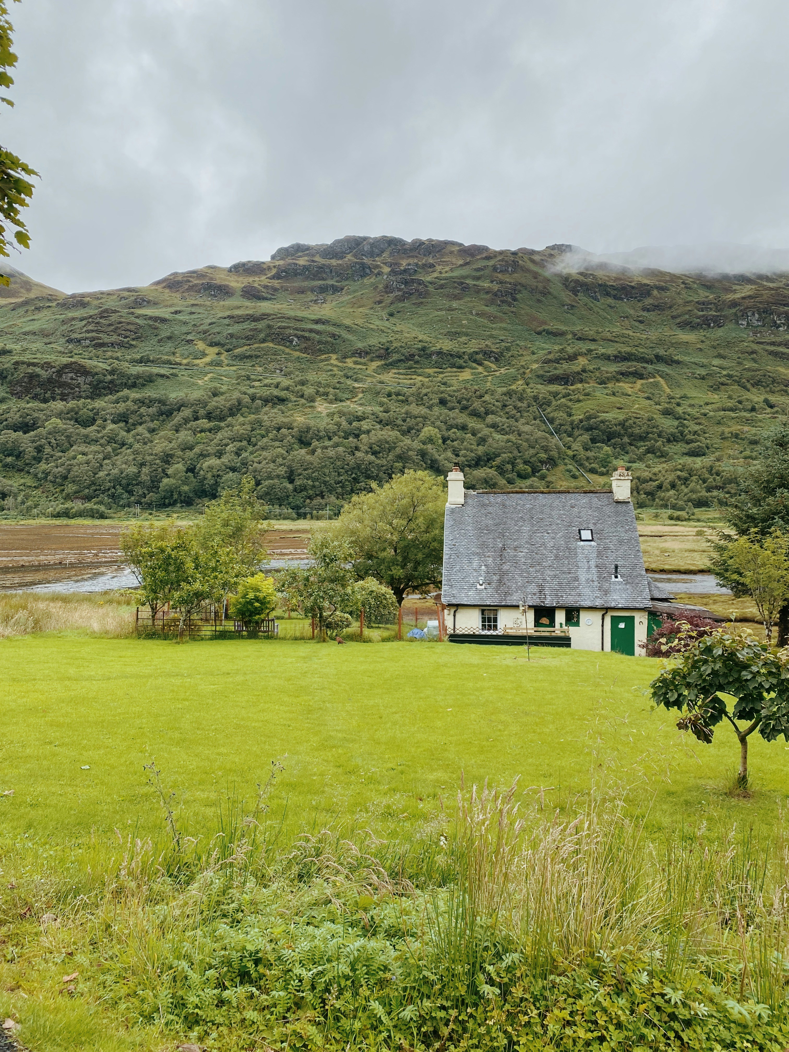 gray and white house on green grass field near mountain during daytime