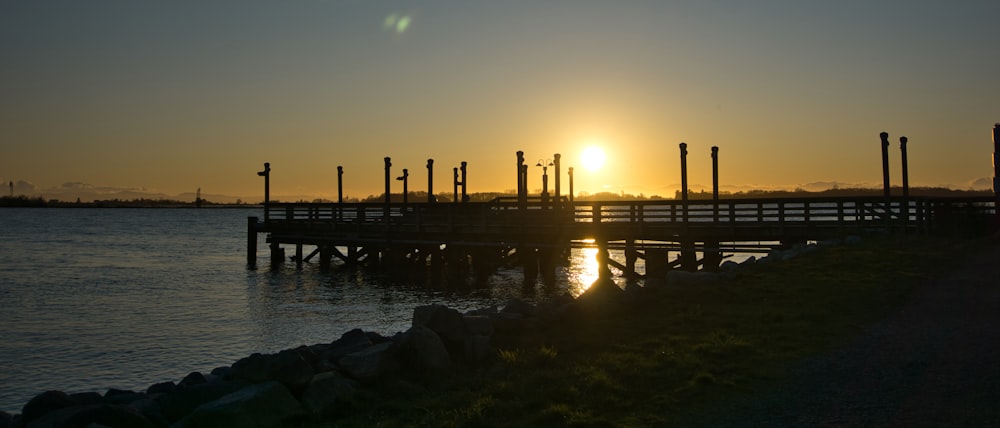 Silhouette des hölzernen Docks auf See während des Sonnenuntergangs