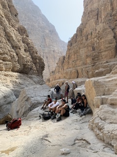 Smiling faces of a small group resting on a rock ledge after a thrilling canyon slide.