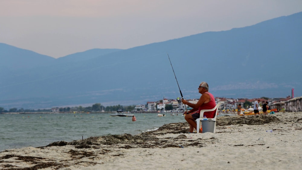 man in red shirt sitting on white and blue boat on beach during daytime