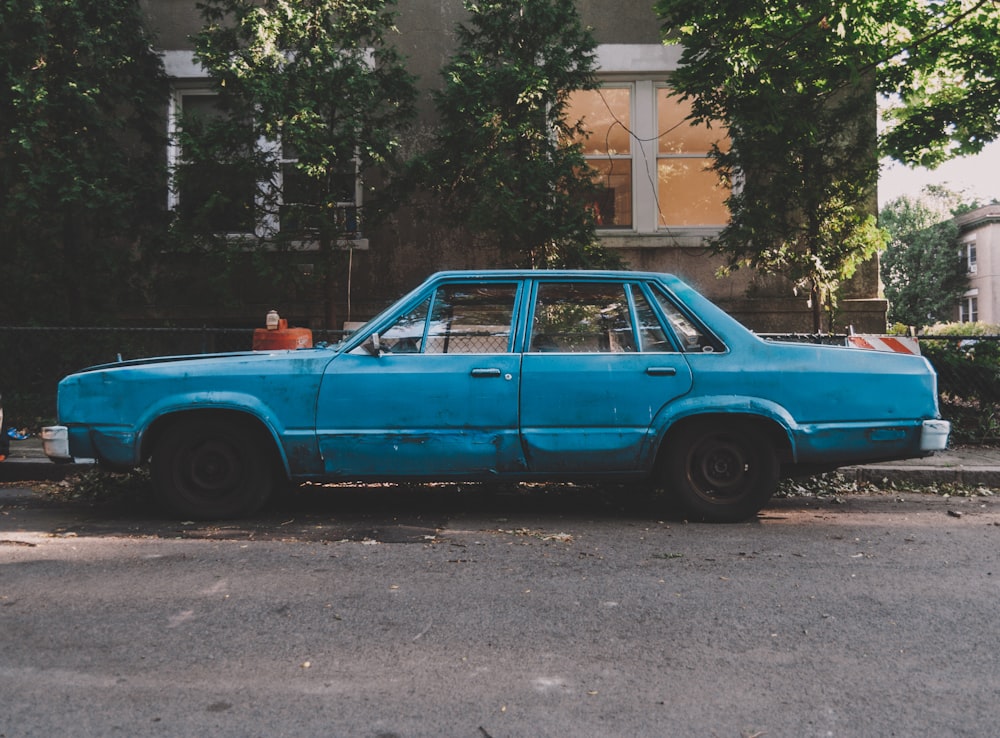 blue sedan parked on gray concrete road during daytime