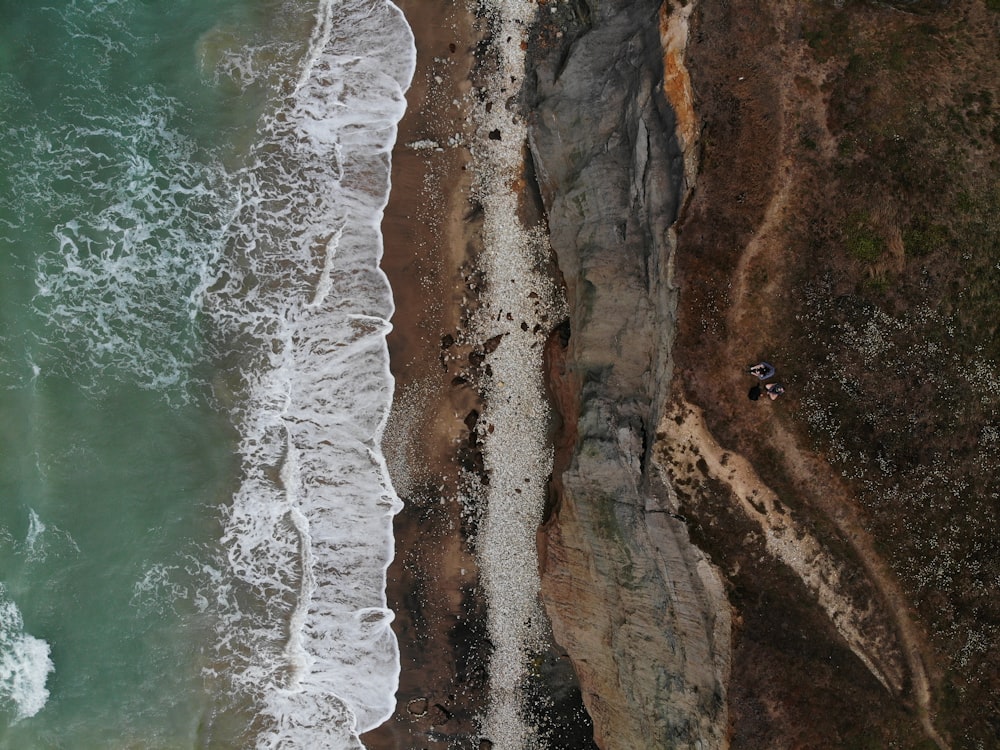 montanha rochosa marrom ao lado do corpo de água durante o dia