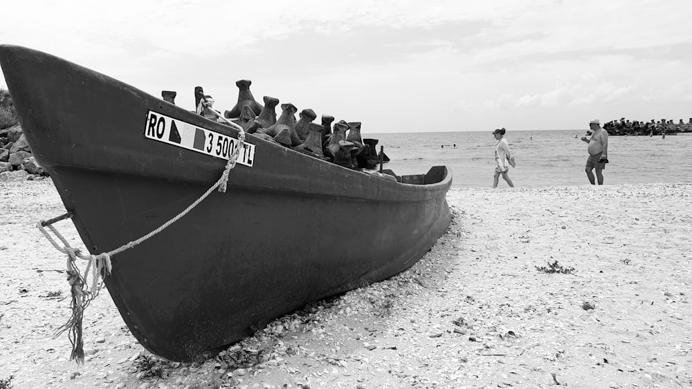 grayscale photo of people riding boat on beach