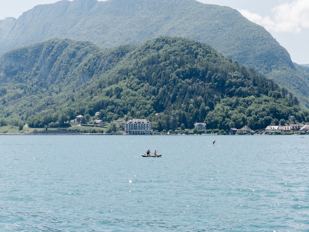 people riding on boat on sea near mountain during daytime