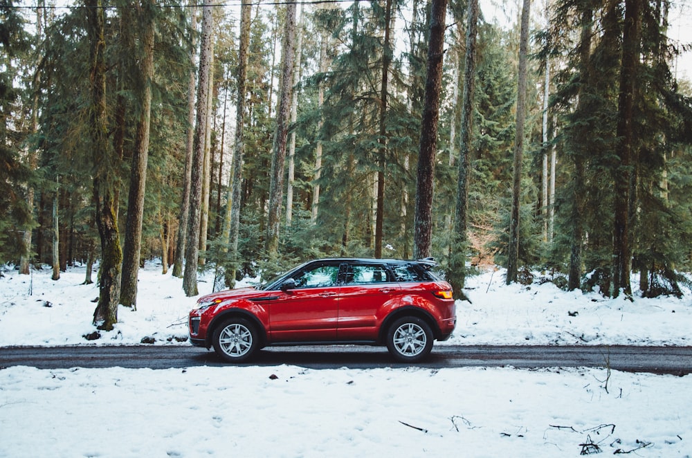 SUV rojo en una carretera cubierta de nieve durante el día