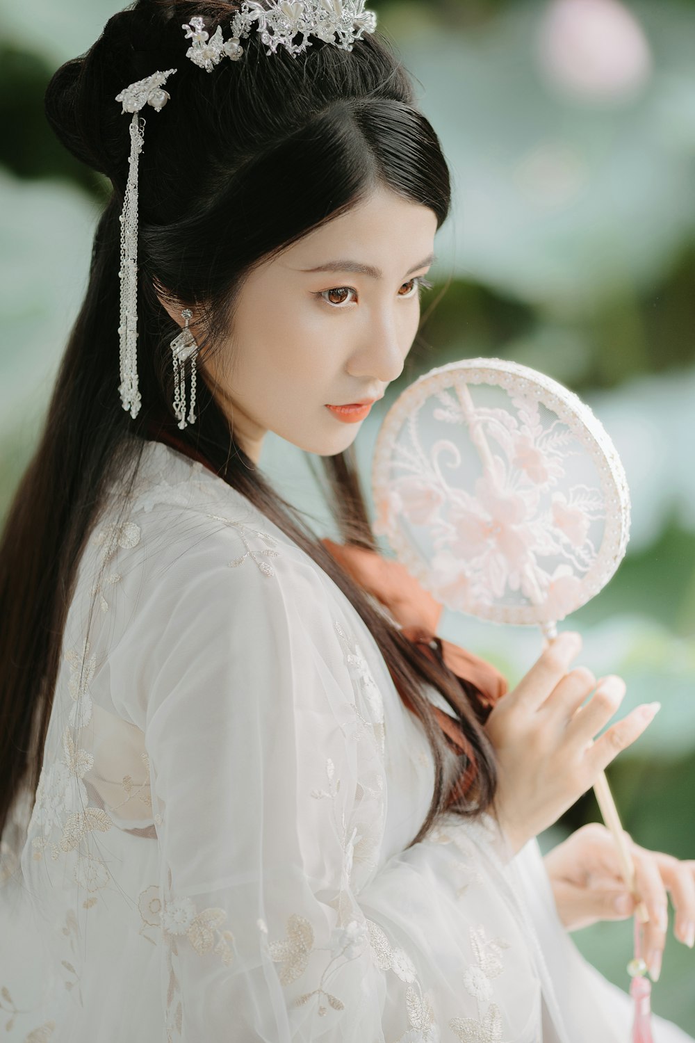 woman in white long sleeve shirt holding white floral hand fan