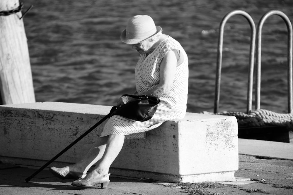 woman in white long sleeve shirt and white pants sitting on concrete bench