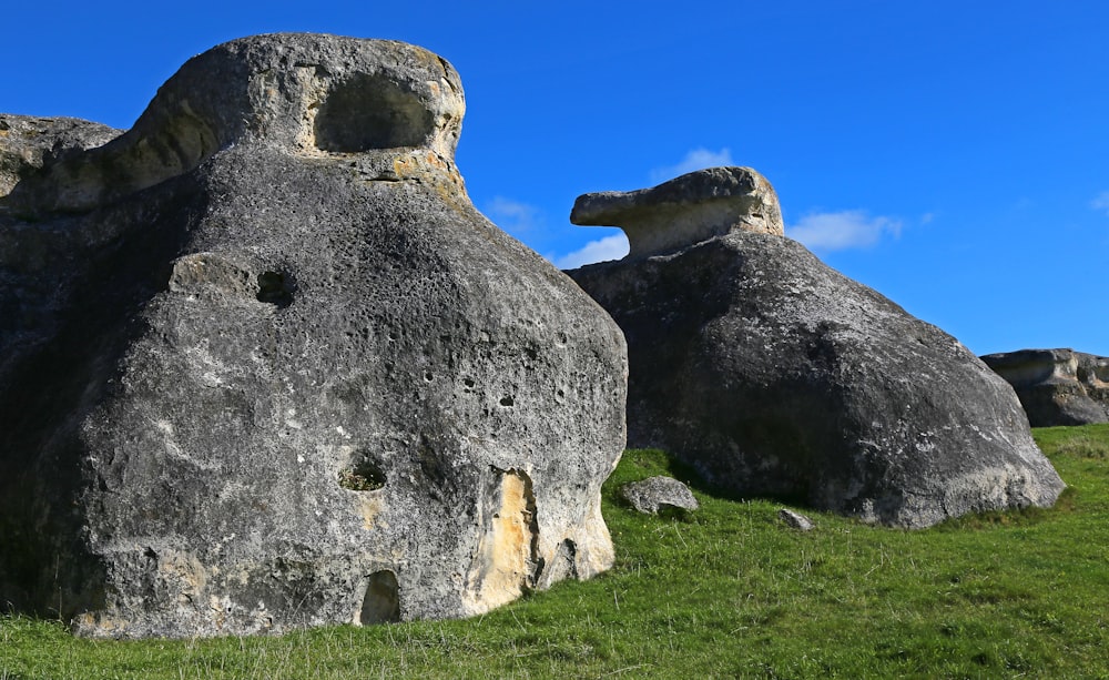 gray rock formation on green grass field under blue sky during daytime